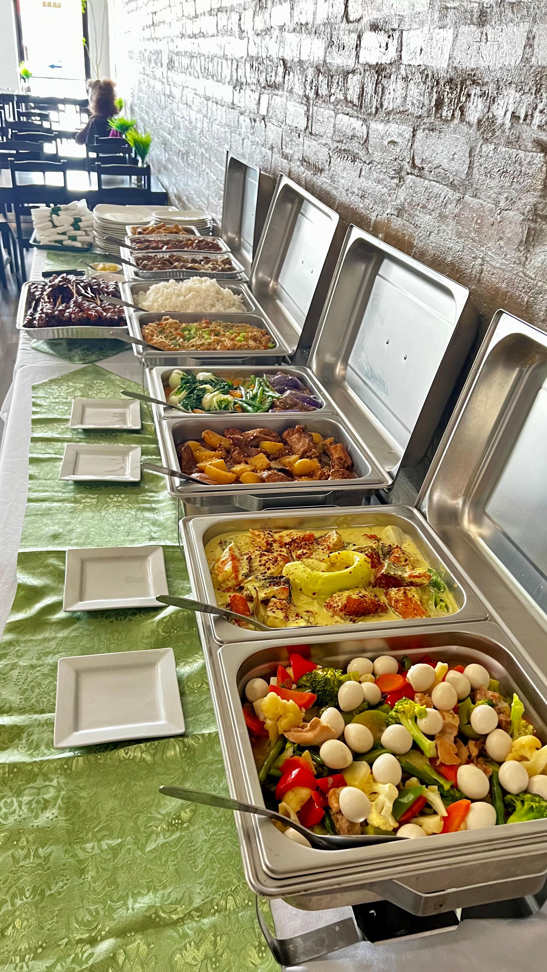 Buffet line of hot trays with mixed vegetables, quail eggs, and curry