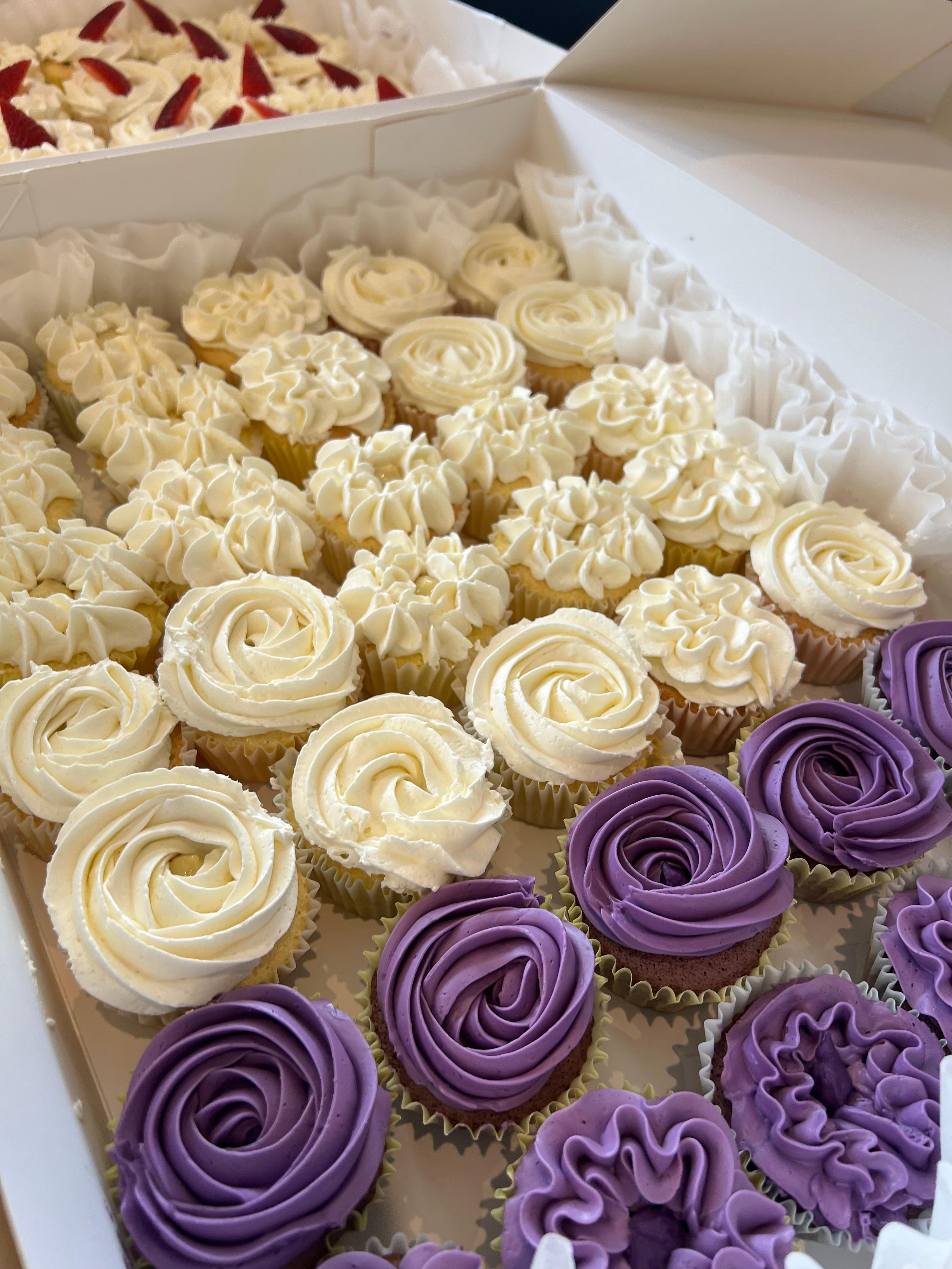 Assorted vanilla and purple buttercream cupcakes with rose and swirl tops